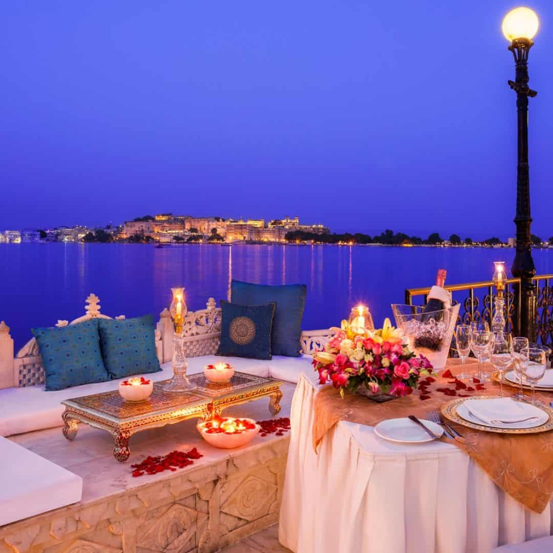 A beautifully arranged table for a romantic dinner, featuring candles and flowers, with a view of the lake at Jag Mandir, India A beautifully arranged table for a romantic dinner, featuring candles and flowers, with a view of the lake at Jag Mandir, India
