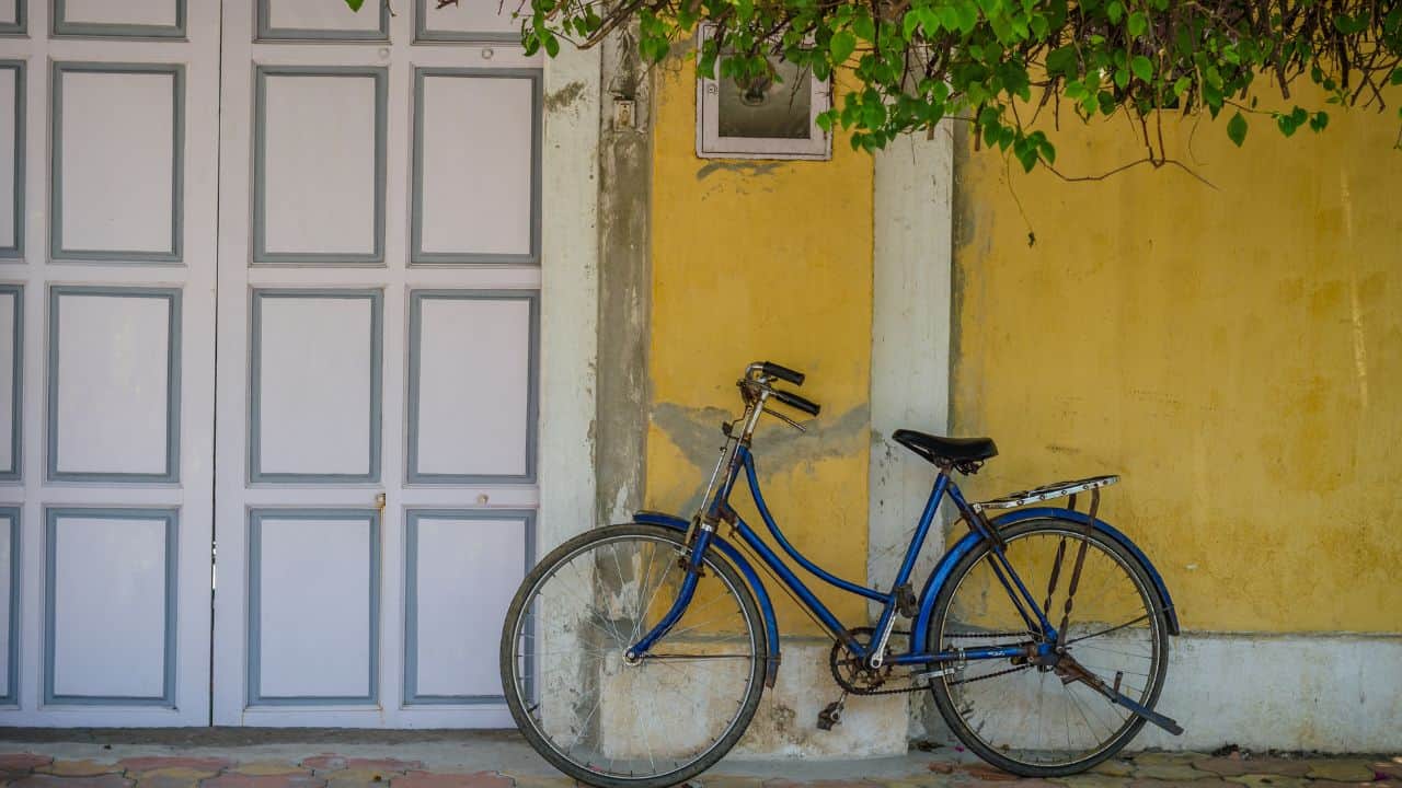A-blue-bicycle-leans-against-a-vibrant-yellow-wall-in-Pondicherry-showcasing-a-colorful-urban-scene.jpg