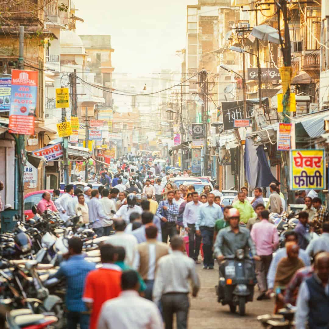 A bustling street in Jaipur, India, filled with pedestrians and motorcycles navigating through the crowd A bustling street in Jaipur, India, filled with pedestrians and motorcycles navigating through the crowd