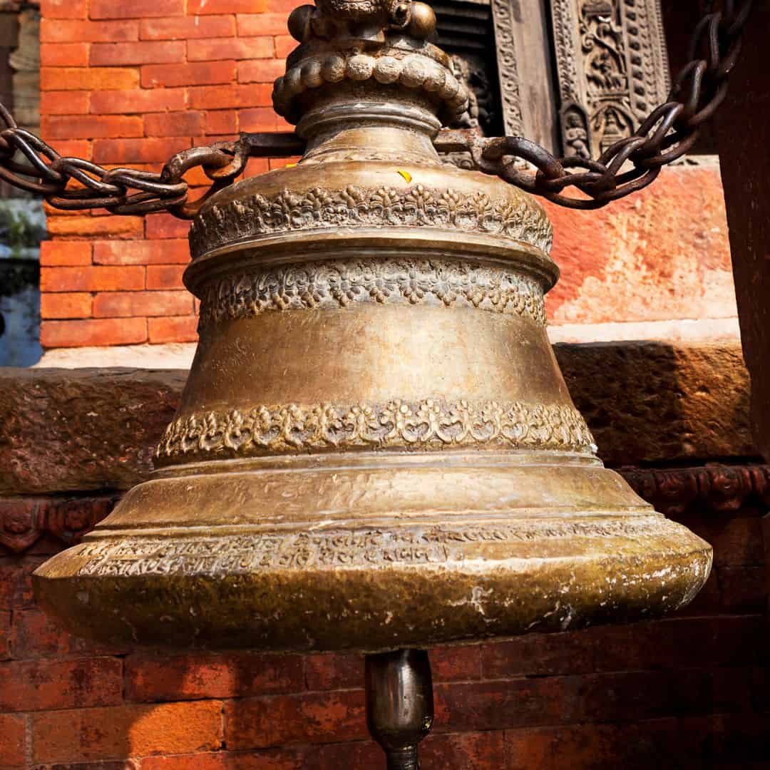 A large bell hangs from a chain outside a building in Varanasi, India, showcasing traditional architecture A large bell hangs from a chain outside a building in Varanasi, India, showcasing traditional architecture