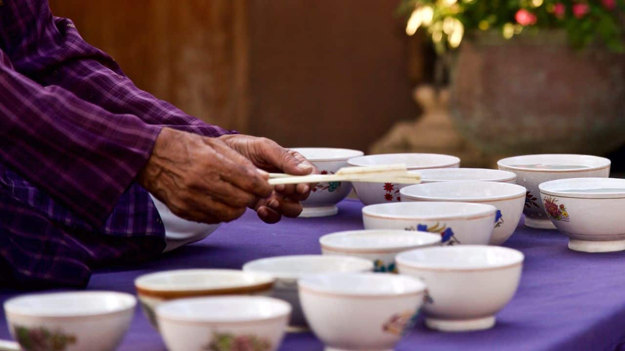 A-man-holds-a-spoon-over-a-bowl-of-tea-at-Jag-Mandir-India.jpg