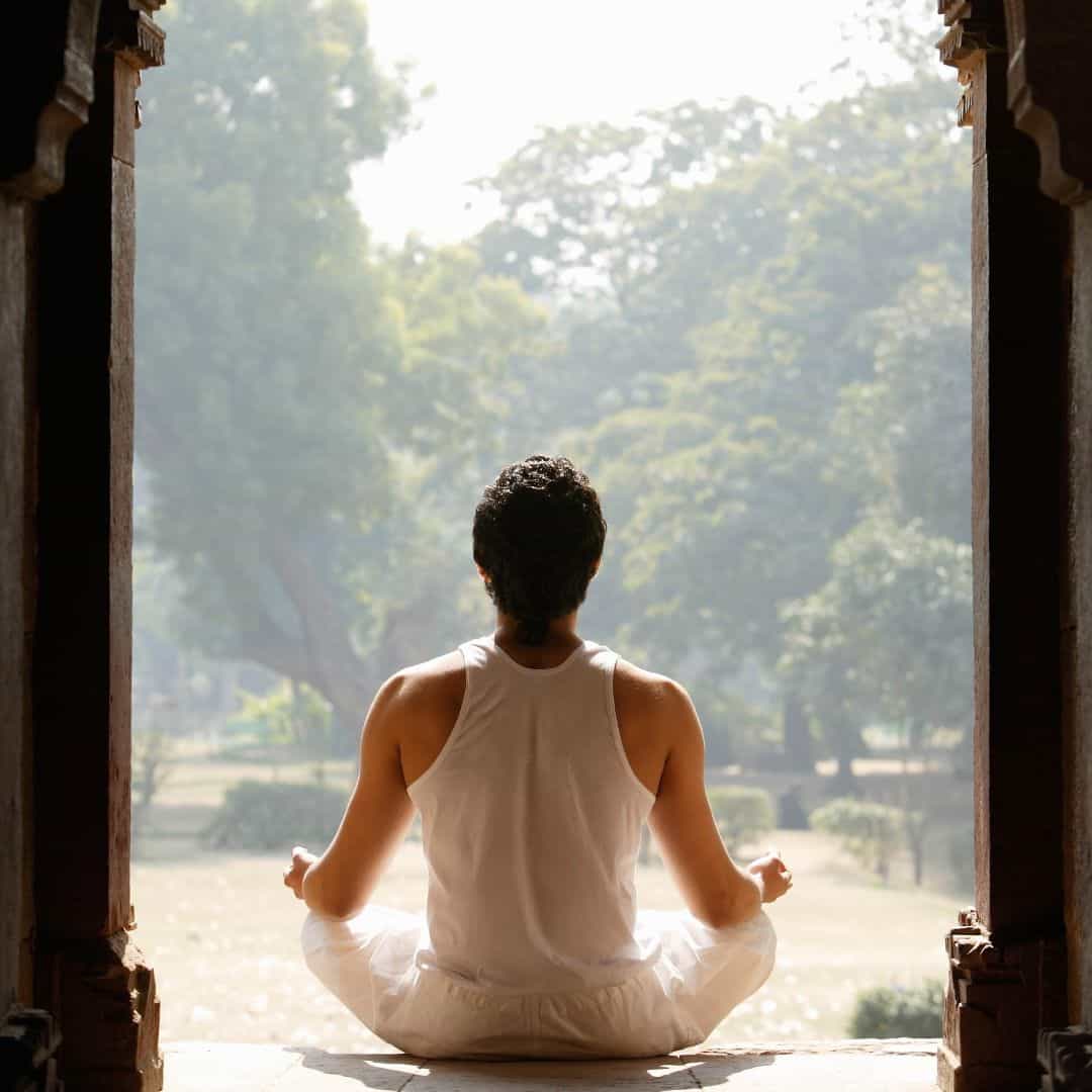 A man in a meditation pose sits peacefully in front of a doorway, embodying the yoga of Varanasi A man in a meditation pose sits peacefully in front of a doorway embodying the Yoga of Varanasi