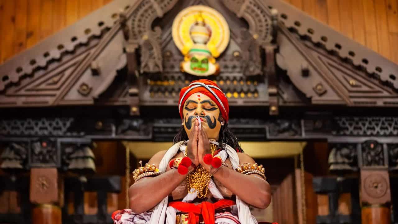 A-man-in-traditional-Indian-attire-prays-during-a-Kathakali-dance-performance-in-India.jpg