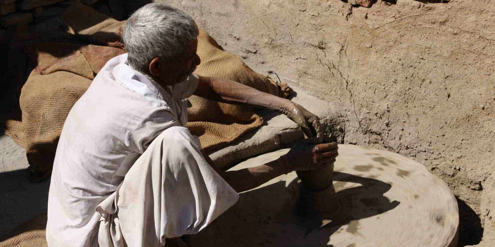 A-man-shapes-a-clay-pot-on-a-wheel-in-Chanoud-Garh-India.jpg