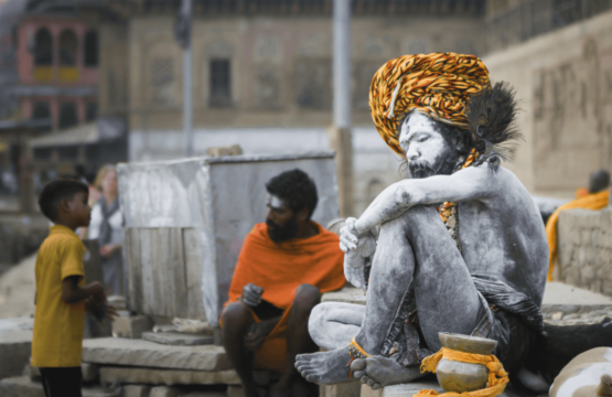 A-man-sitting-on-the-ground-in-Varanasi-India-capturing-a-moment-of-local-life-and-culture-555x360.png