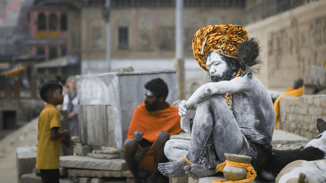 A-man-sitting-on-the-ground-in-Varanasi-India-capturing-a-moment-of-local-life-and-culture.png