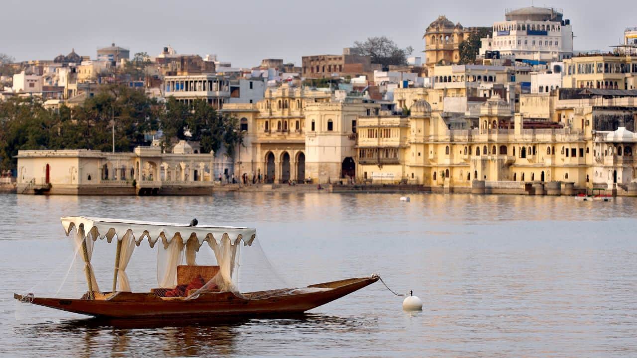 A-serene-boat-on-the-water-in-front-of-Udaipur-city-India-highlighting-the-urban-landscape-and-natural-beauty.jpg