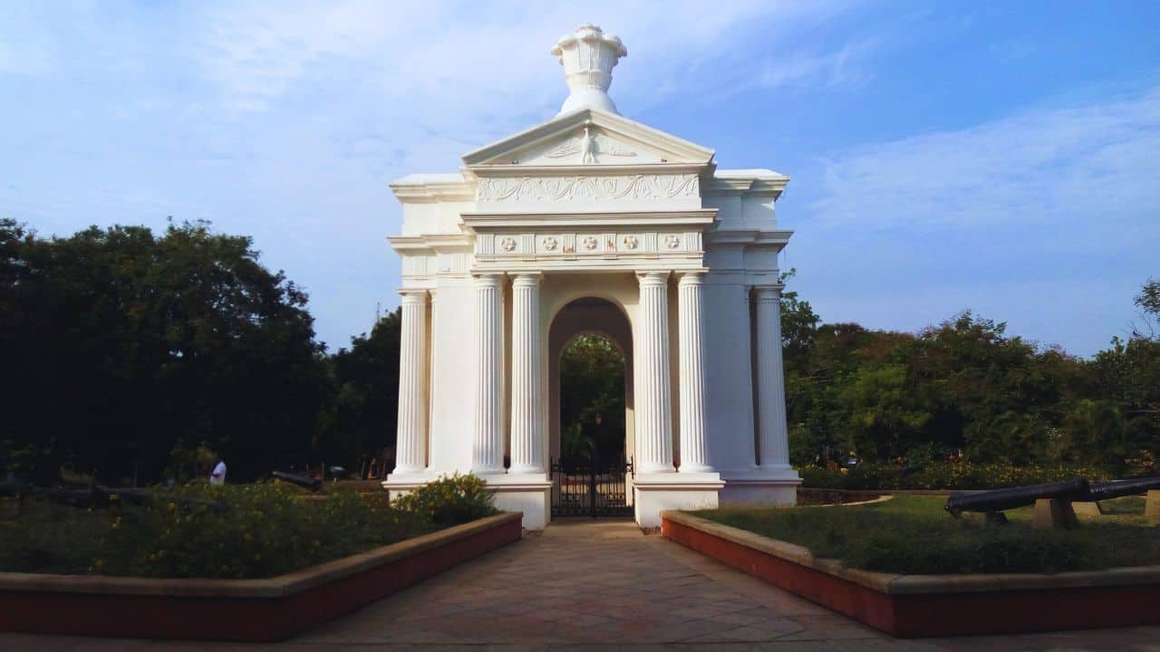A-white-tower-monument-is-situated-in-the-center-of-a-park-in-Pondicherry-framed-by-trees-and-open-space.jpg