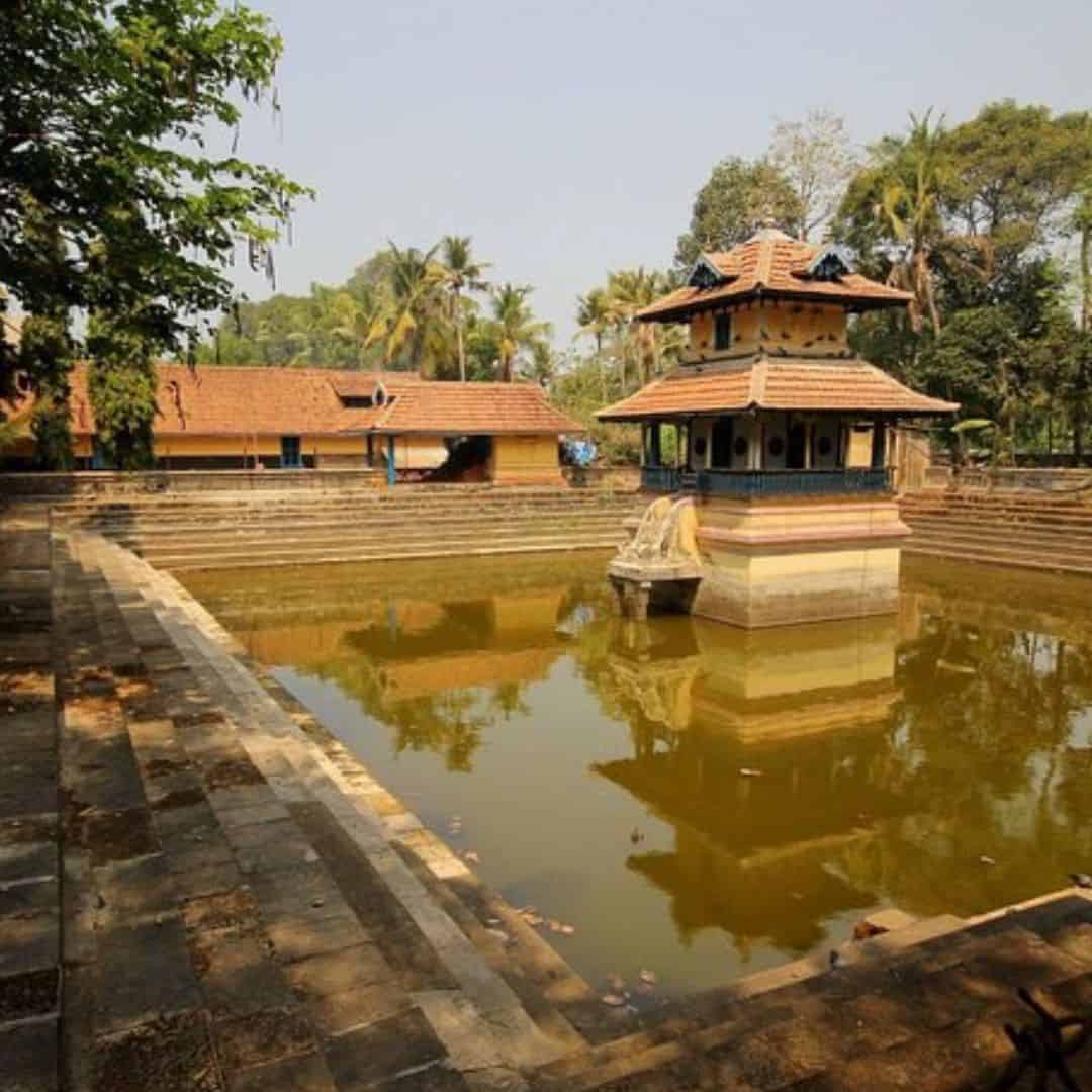 An ancient temple surrounded by a serene pond, located in Muziris, India An ancient temple surrounded by a serene pond located In Muziris India
