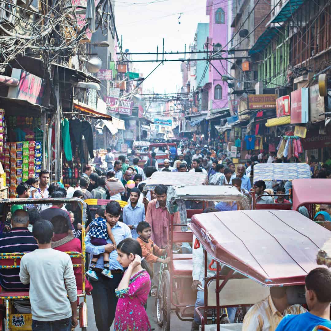 Crowded Old Delhi street scene with numerous people walking and rickshaws Crowded old Delhi street with numerous people walking and rickshaws