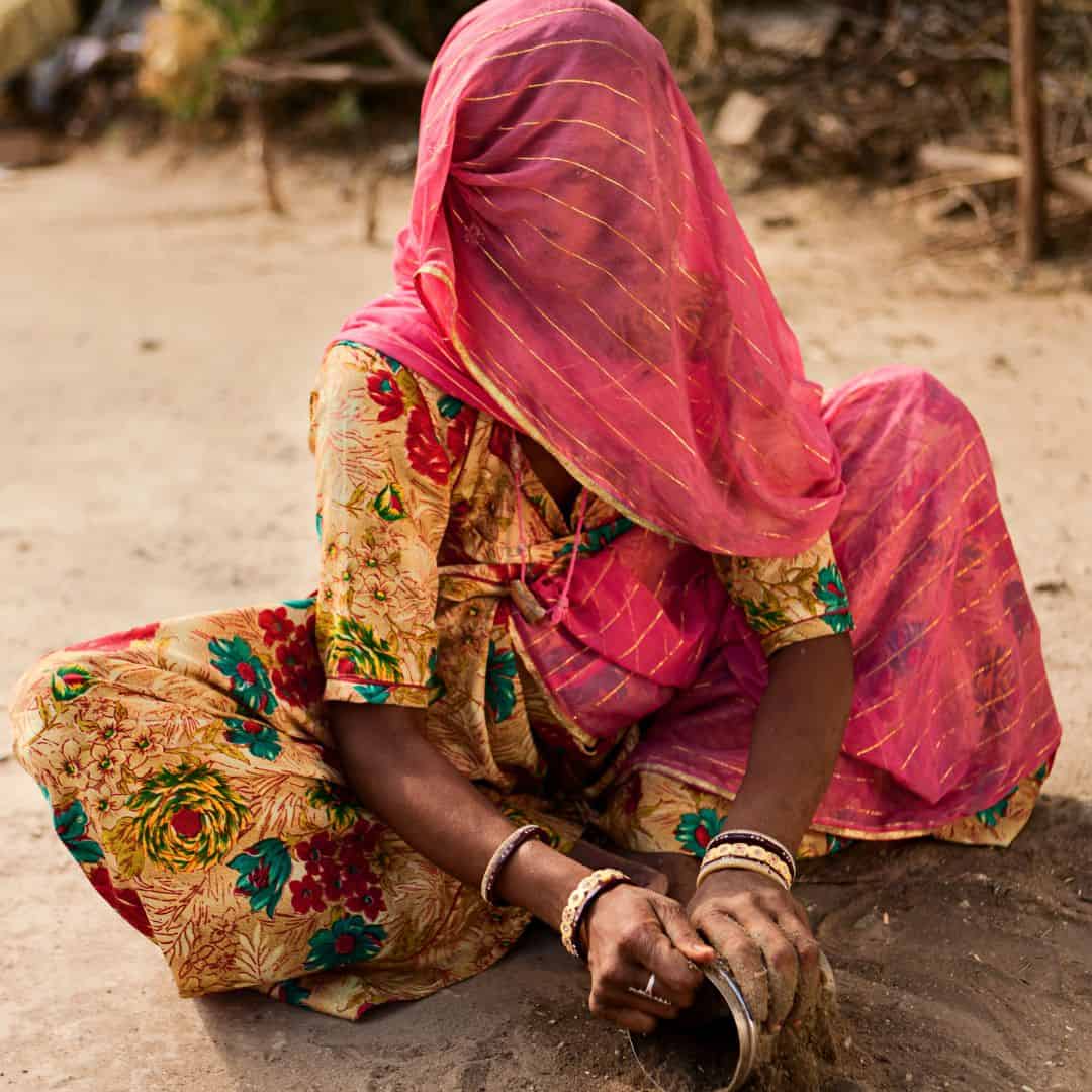 In Bishnoi Village, India, a woman wearing a colorful sari sits on the ground In Bishnoi Village, India, a woman wearing a colorful sari sits on the ground