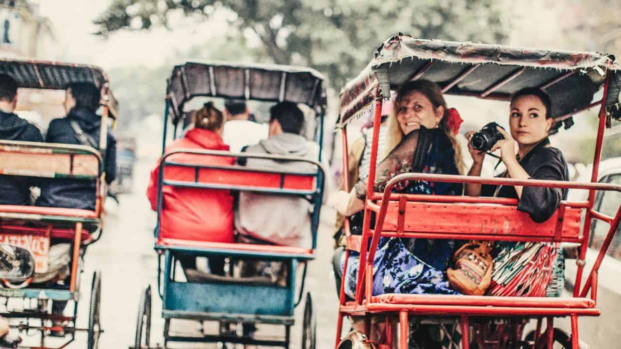Tourists-experiencing-a-vibrant-rickshaw-ride-in-Old-Delhi-surrounded-by-colorful-street-scenes.jpg