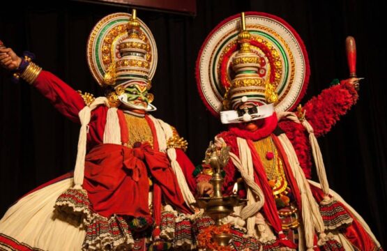 Two-dancers-in-vibrant-Kathakali-costumes-performing-on-stage-showcasing-traditional-Indian-dance-555x360.jpg