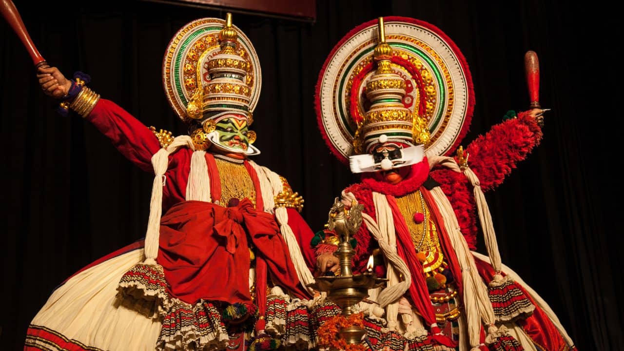Two-dancers-in-vibrant-Kathakali-costumes-performing-on-stage-showcasing-traditional-Indian-dance.jpg