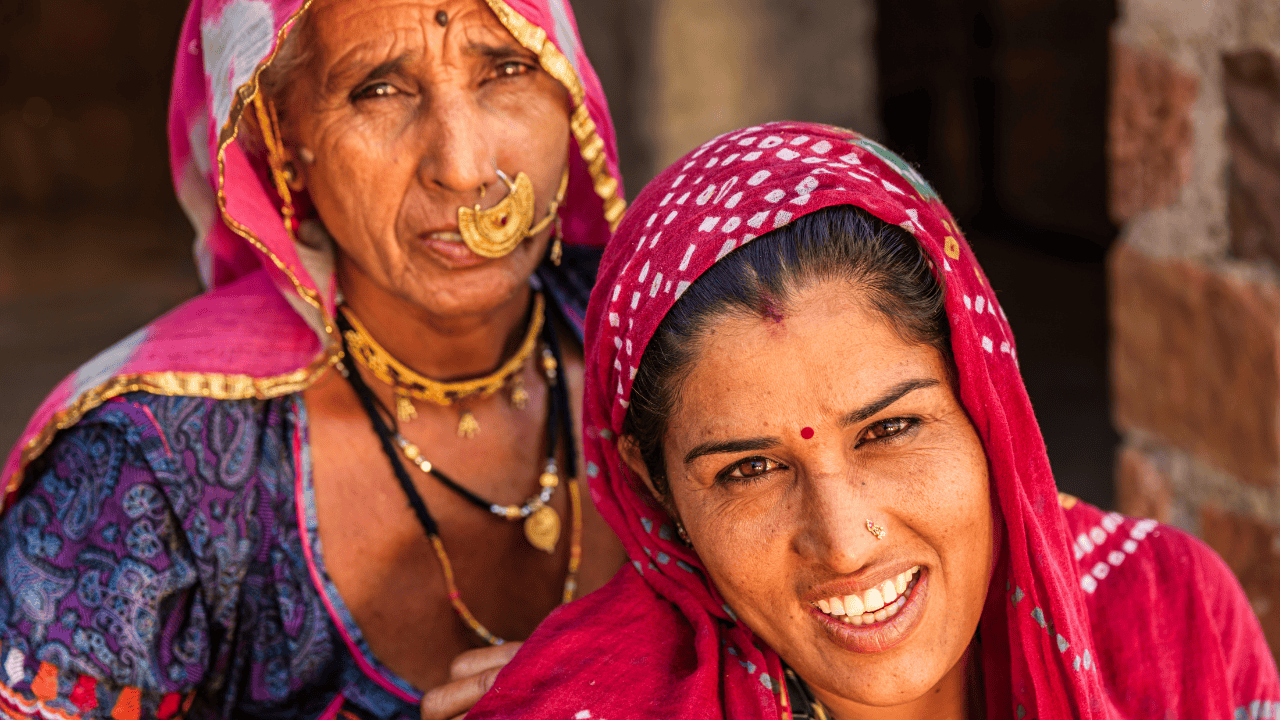 Two-women-in-colorful-saris-smiling-at-the-camera-in-Bishnoi-Village-India.png
