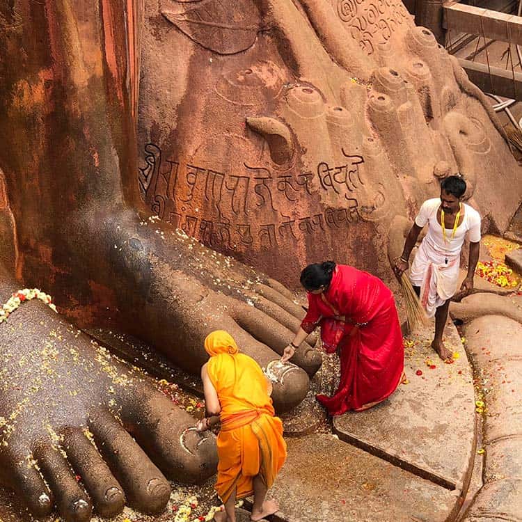 People are cleaning the feet of a statue in India, showcasing a cultural ritual of respect and devotion People are cleaning the feet of a statue in India showcasing a cultural ritual of respect and devotion